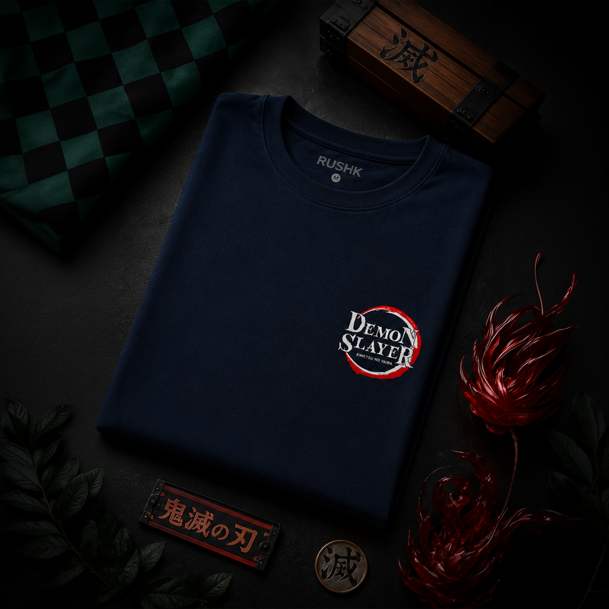 Navy blue t-shirt with 'Demon Slayer' logo on a dark surface with decorative elements.