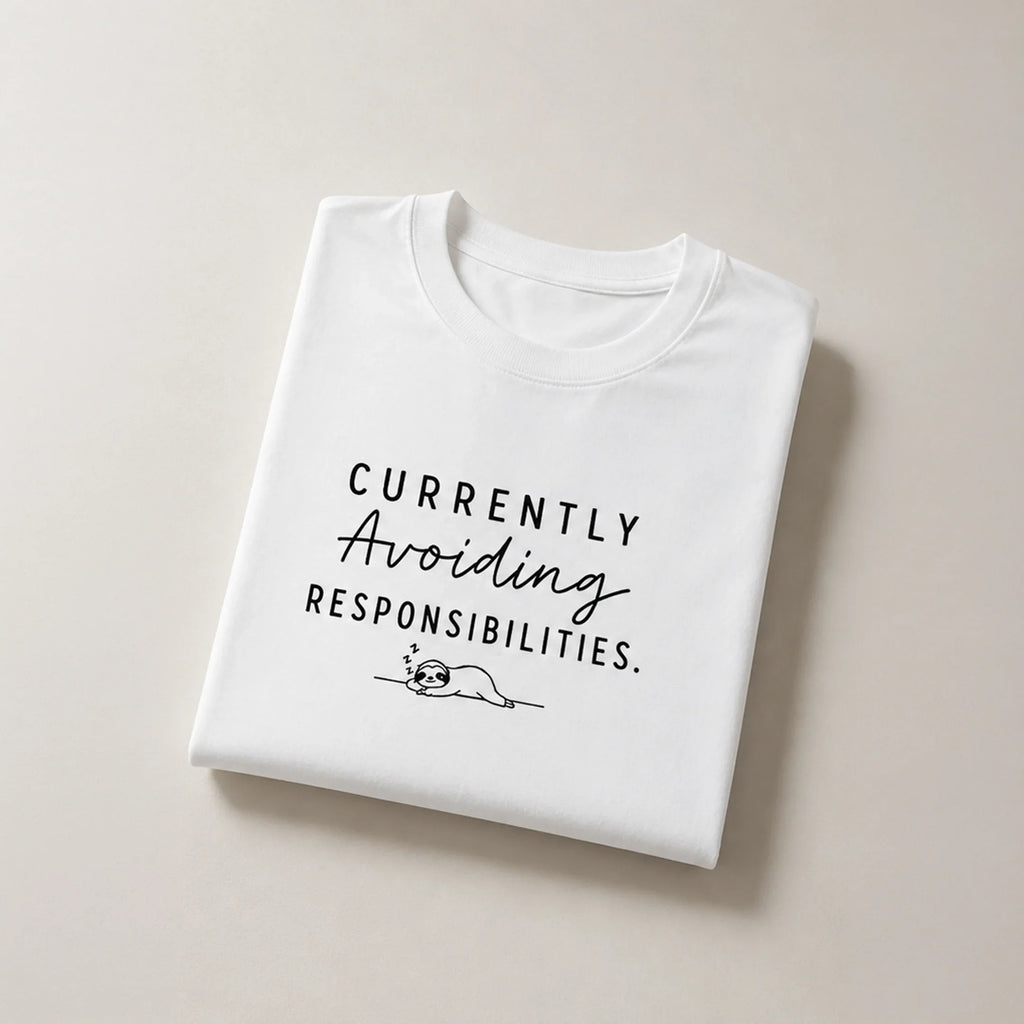 White graphic tee with 'Currently Avoiding Responsibilities' text and sleeping sloth design, bold streetwear style