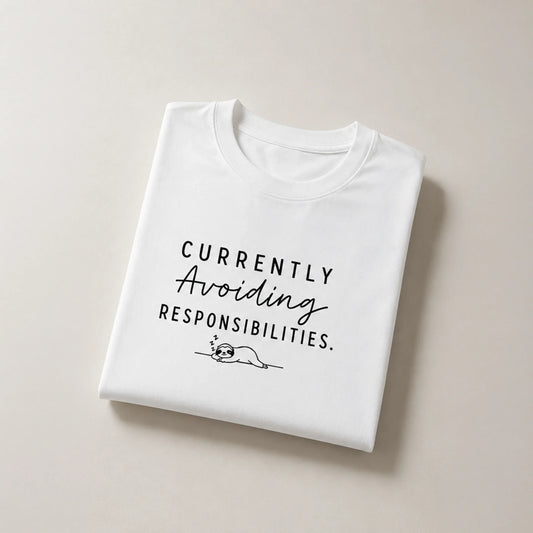 White graphic tee with 'Currently Avoiding Responsibilities' text and sleeping sloth design, bold streetwear style